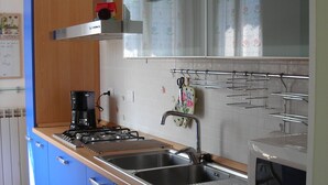 Una cucina con mobili blu, un lavello in acciaio inossidabile, un forno a microonde e un fornello a gas.