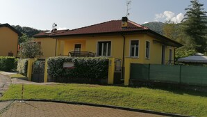 Una casa gialla con tetto in tegole rosse, un ingresso con cancello e un cartello che indica si tratta di una casa vacanze.