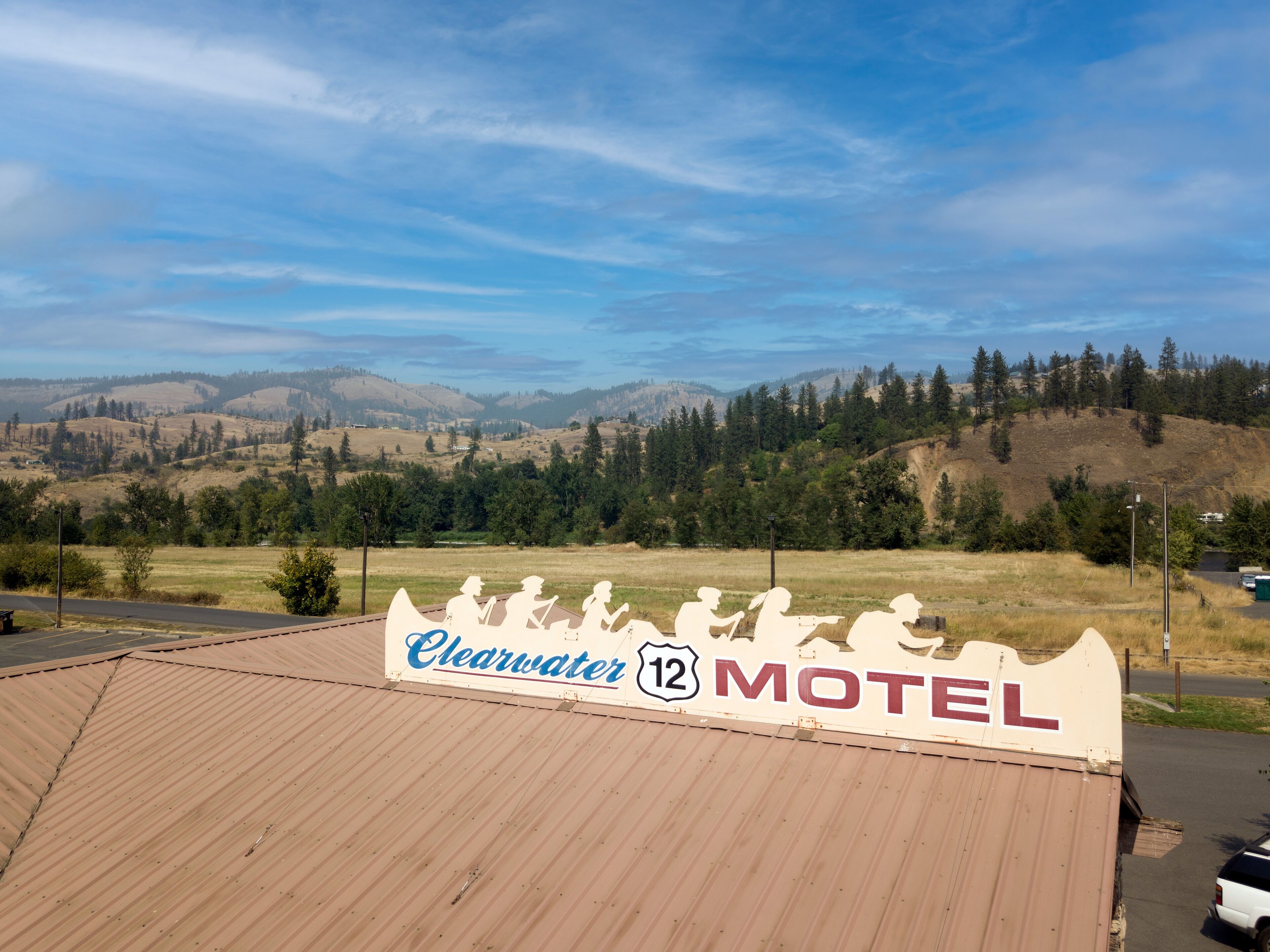 A motel sign with 'Clearwater 12 Motel' and a view of a hilly landscape.