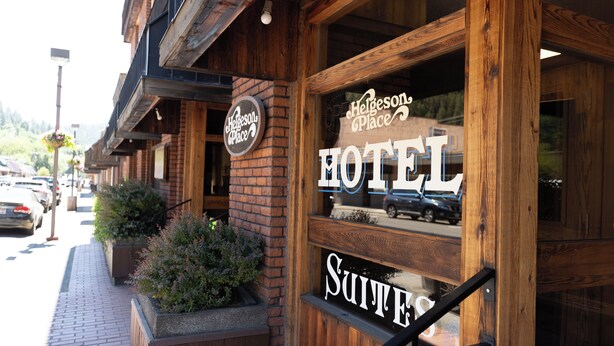 A wooden exterior of a hotel with a sign reading "Hefgeson Place HOTEL SUITES". - Helgeson Place Hotel & Suites (Orofino)
