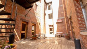 A courtyard with a wooden deck, outdoor seating, and a brick building with a sign indicating a hotel lobby. - Helgeson Place Hotel & Suites (Orofino)