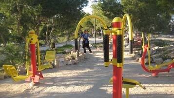 Work out under the shade of lush trees in this outdoor fitness area, featuring a seesaw, climbing structure, and balance beam.