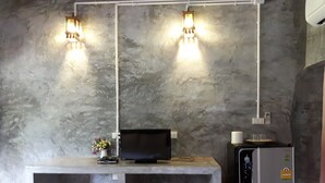 Una cocina con encimera, refrigerador, televisor y dos luces empotradas.
