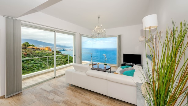 A modern living room with a large sliding glass door leading to a balcony with a sea view. - Villa Maiquetia, villa with heated swimming pool (Sta Úrsula)