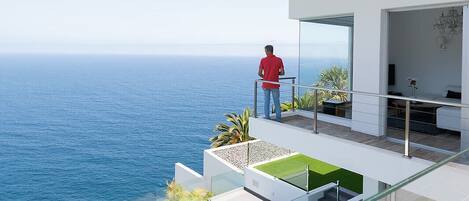 Ein modernes Haus mit einem Glasbalkon mit Blick auf das Meer.