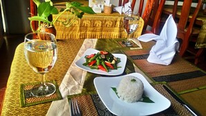 Una mesa con un plato de vegetales salteados, un bol de arroz y una copa de vino blanco.