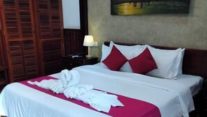 Una habitación de hotel con una cama grande, un armario de madera y un cuadro en la pared.