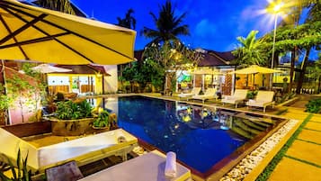 Una piscina al aire libre, sombrillas, sillones reclinables de piscina