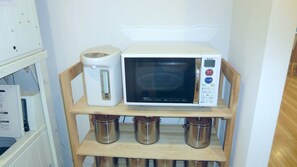A microwave oven on a wooden shelf with a coffee maker beside it. - CVS Bay Hotel Annex (Ichikawa)