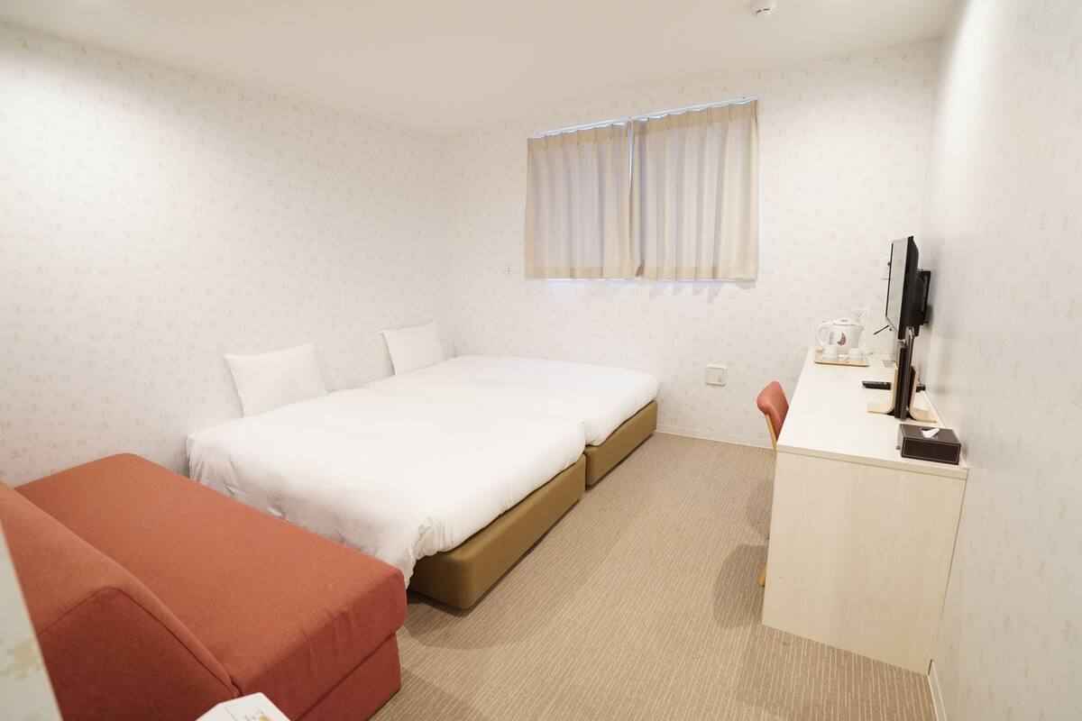 Hotellihuone, jossa on sänky, työpöytä, tuoli ja televisio.