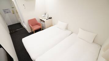 A hotel room with a bed, a desk, a chair, and a small table.