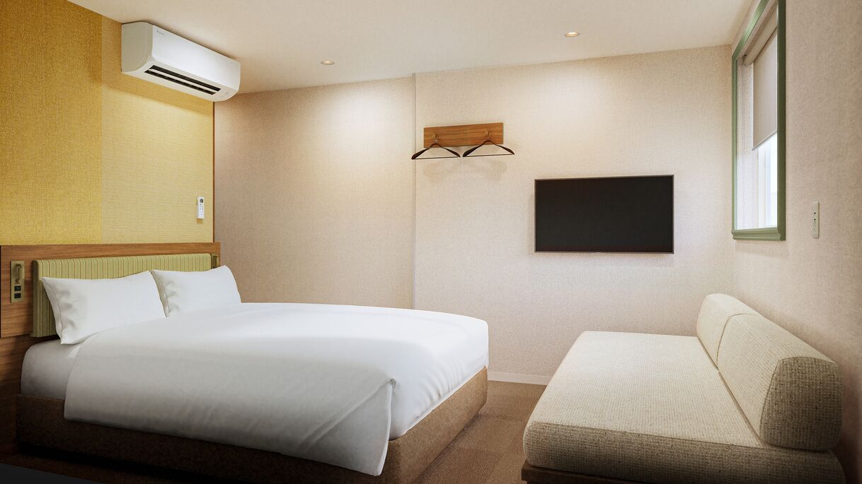 A hotel room with a bed, a sofa, an air conditioning unit, a mounted TV, and a window.
