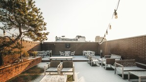 Un patio al aire libre con paredes de ladrillo, mesas y sillas.