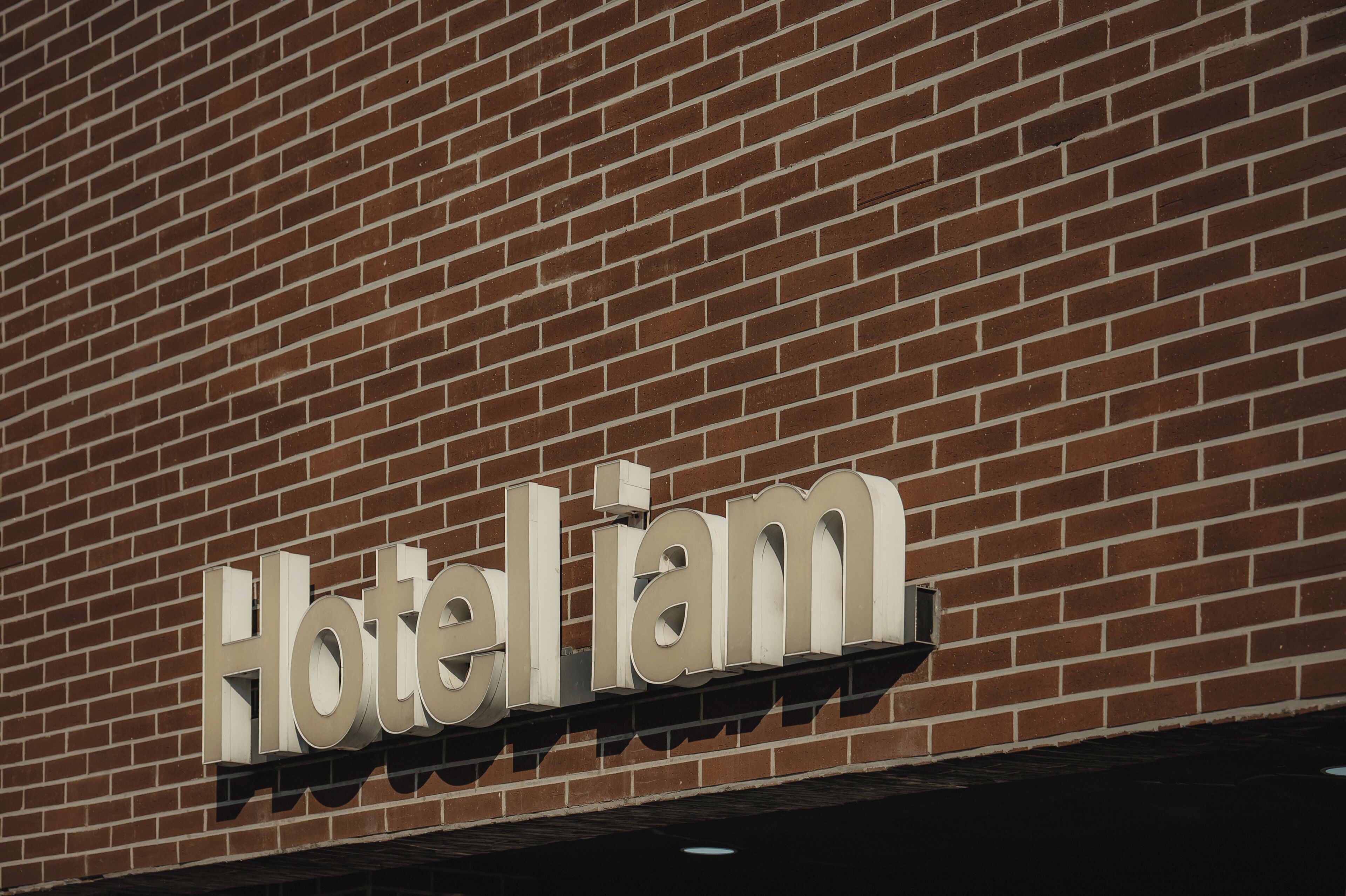 Een hotelschilder met de naam 'Hotel iam' op een bakstenen muur.