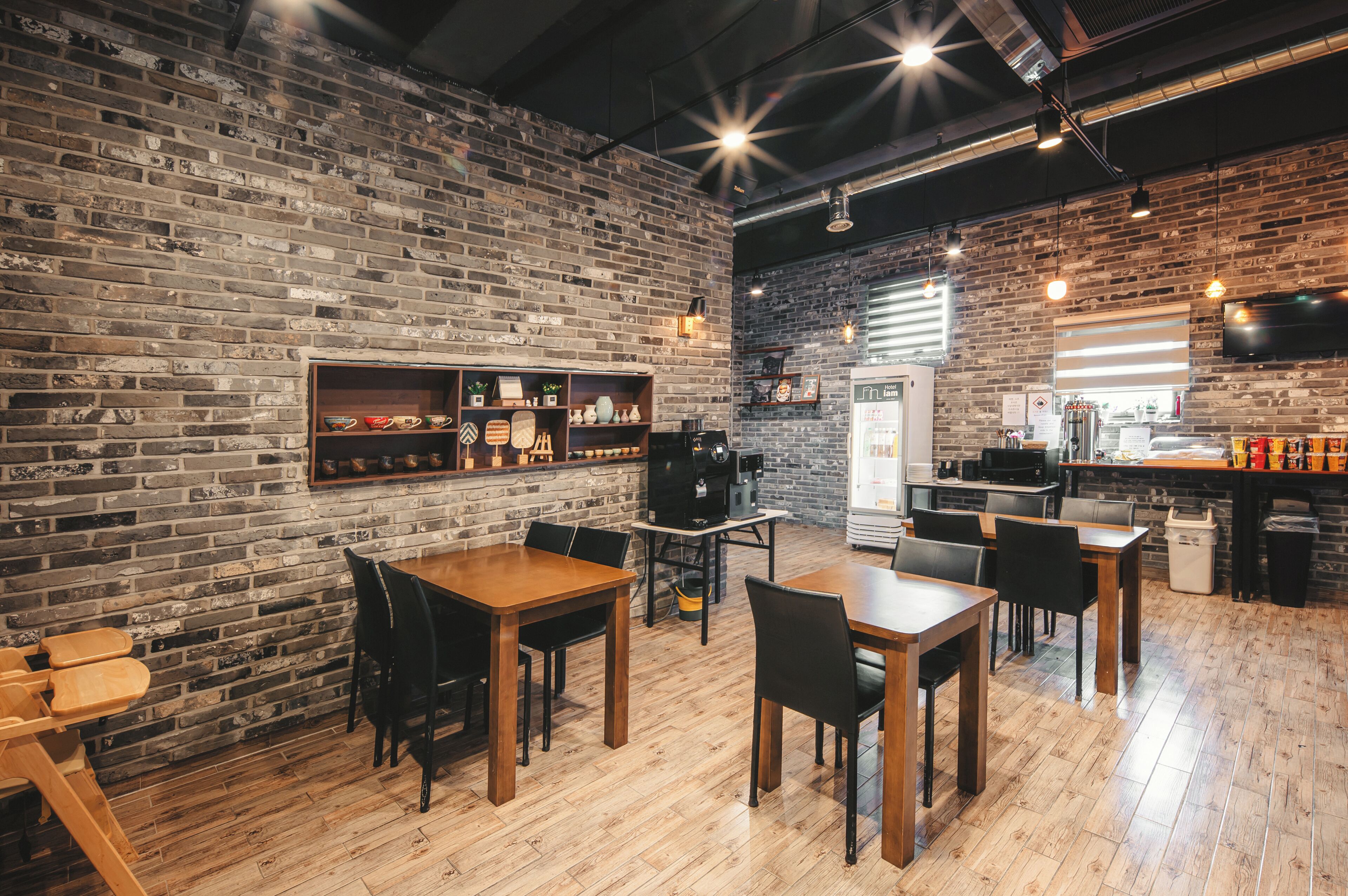 A restaurant with brick walls, wooden tables, and black chairs.