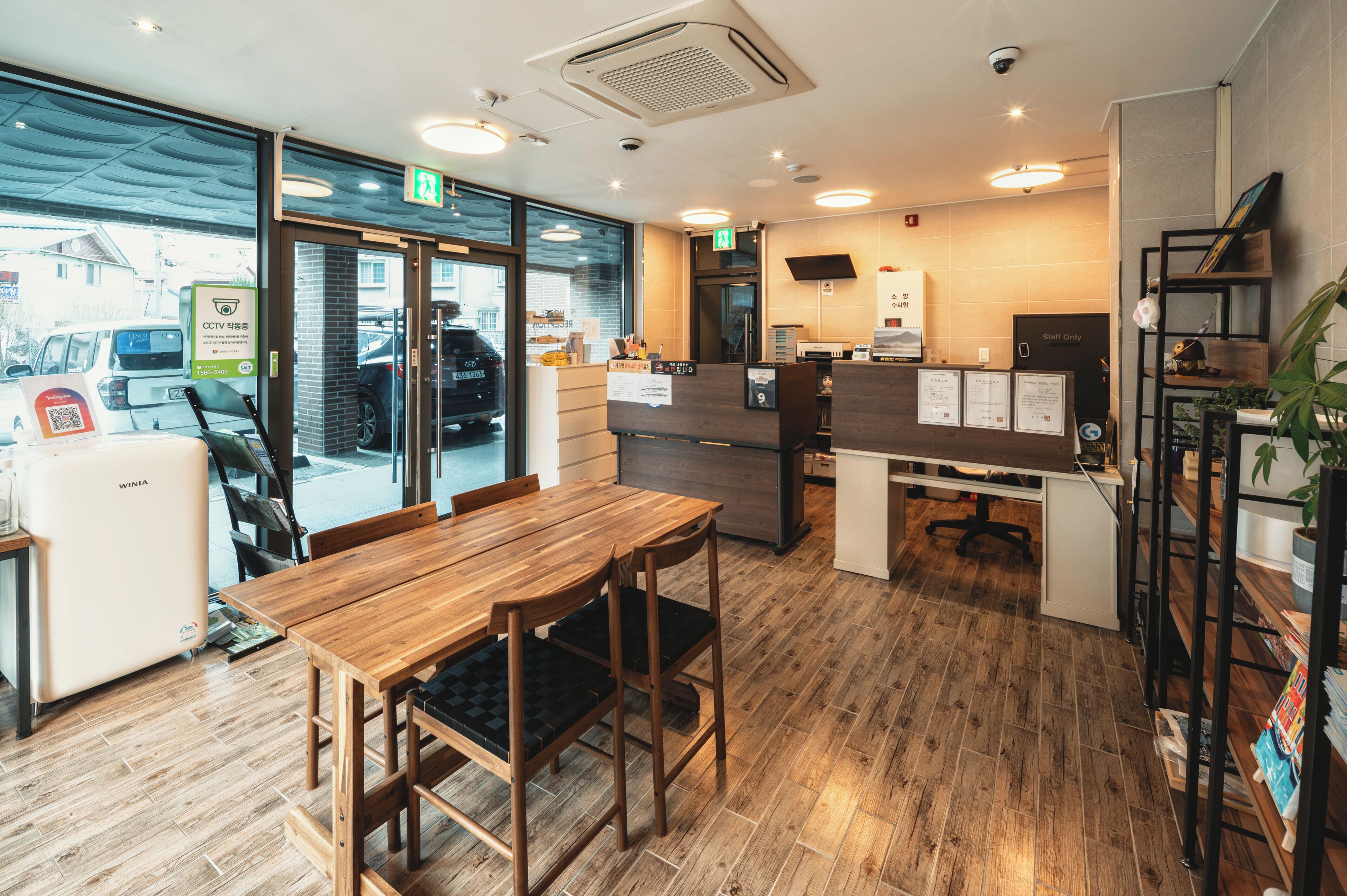 A modern interior with a wooden dining table, chairs, a reception desk, and a counter.