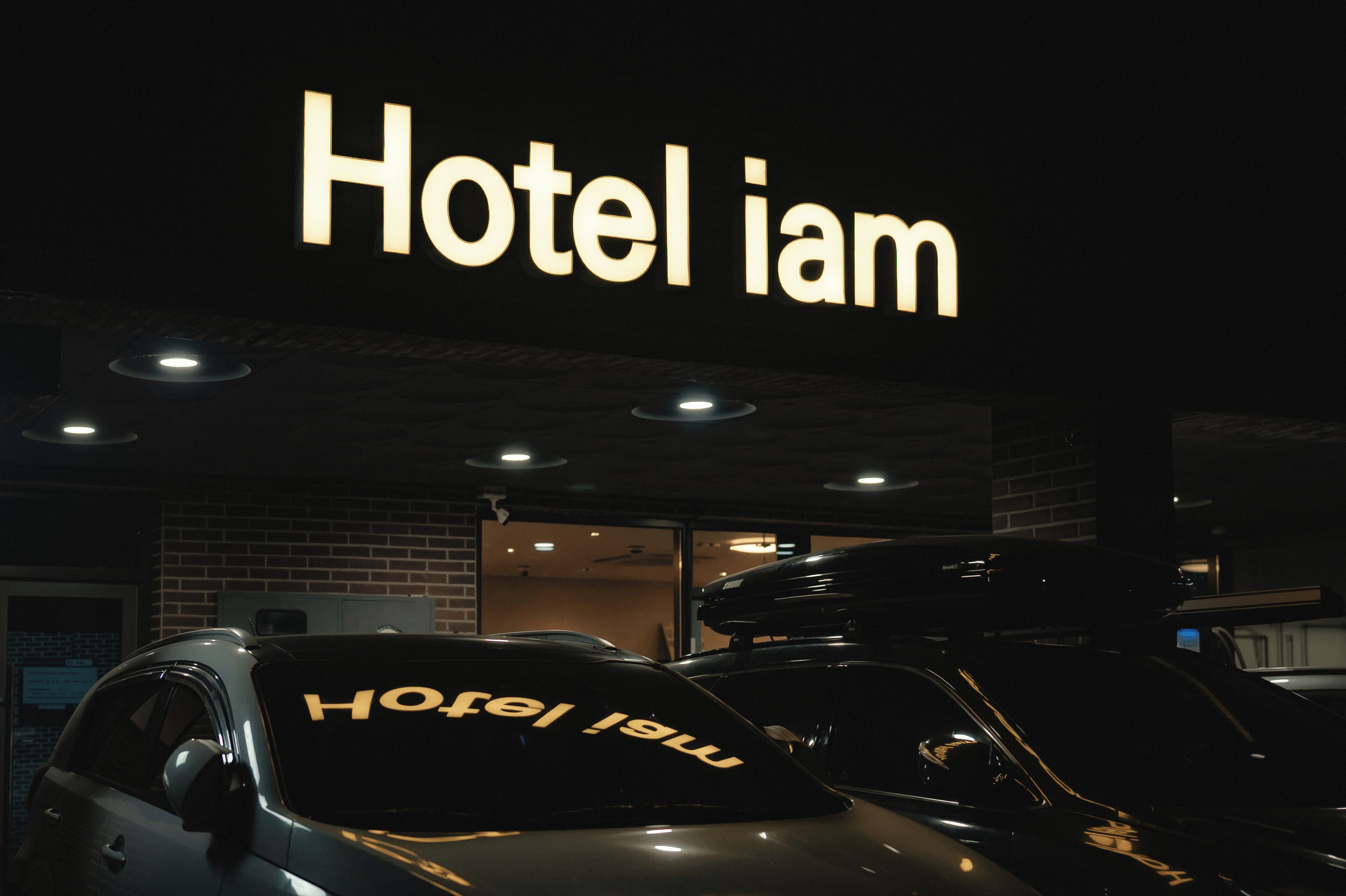 Ein Gebäude mit einem Schild, auf dem 'Hotel iam' steht, und mehreren Autos davor.