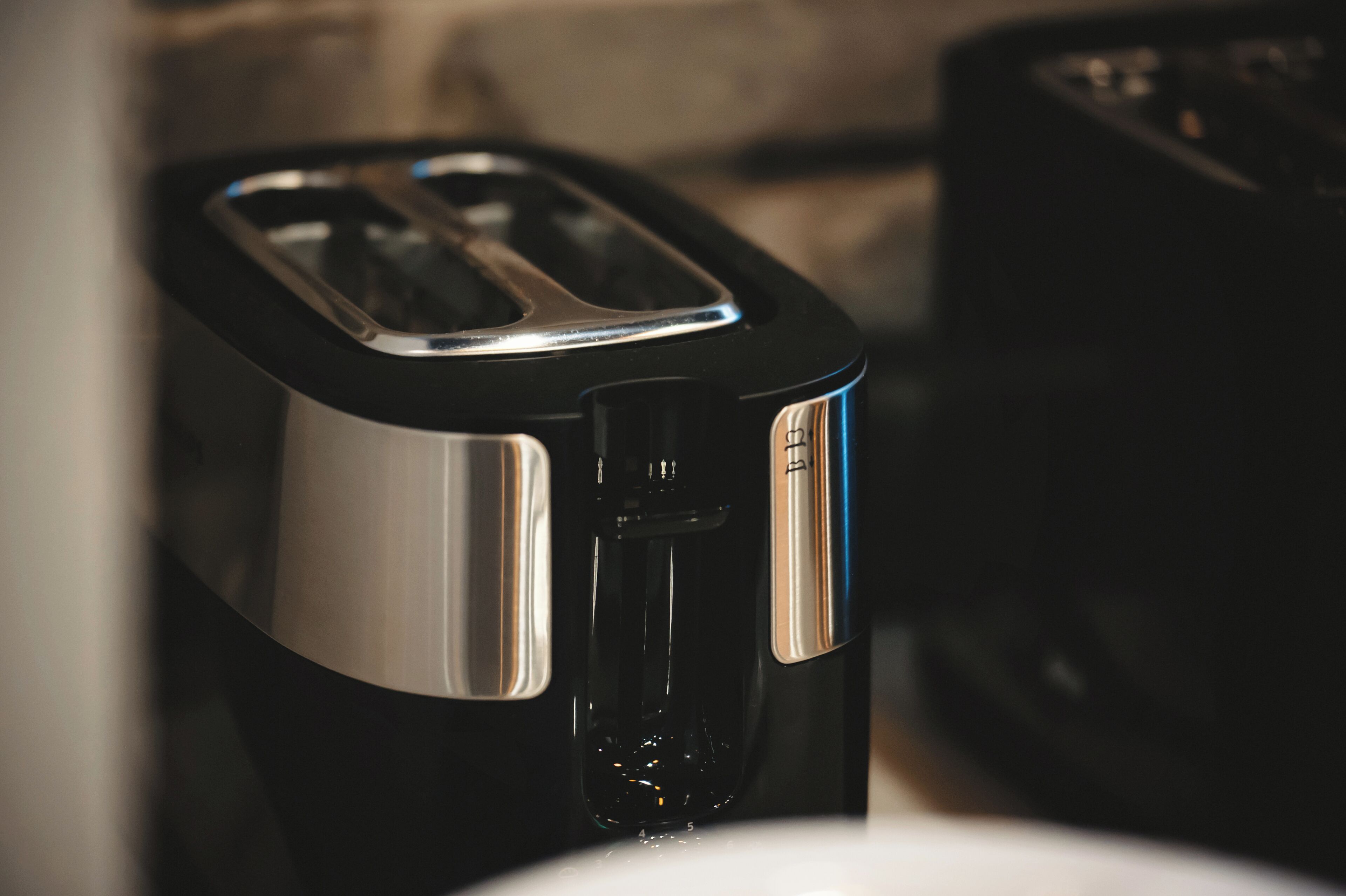 A black and silver toaster with a water reservoir on a kitchen counter.