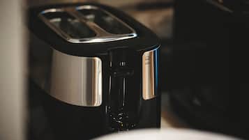 A black and silver toaster with a water reservoir on a kitchen counter.