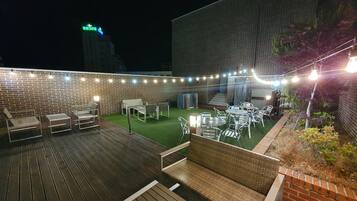 An outdoor patio with a brick wall, string lights, and outdoor furniture.