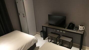 Habitación de hotel con dos camas, televisión, escritorio con cafetera y refrigerador.