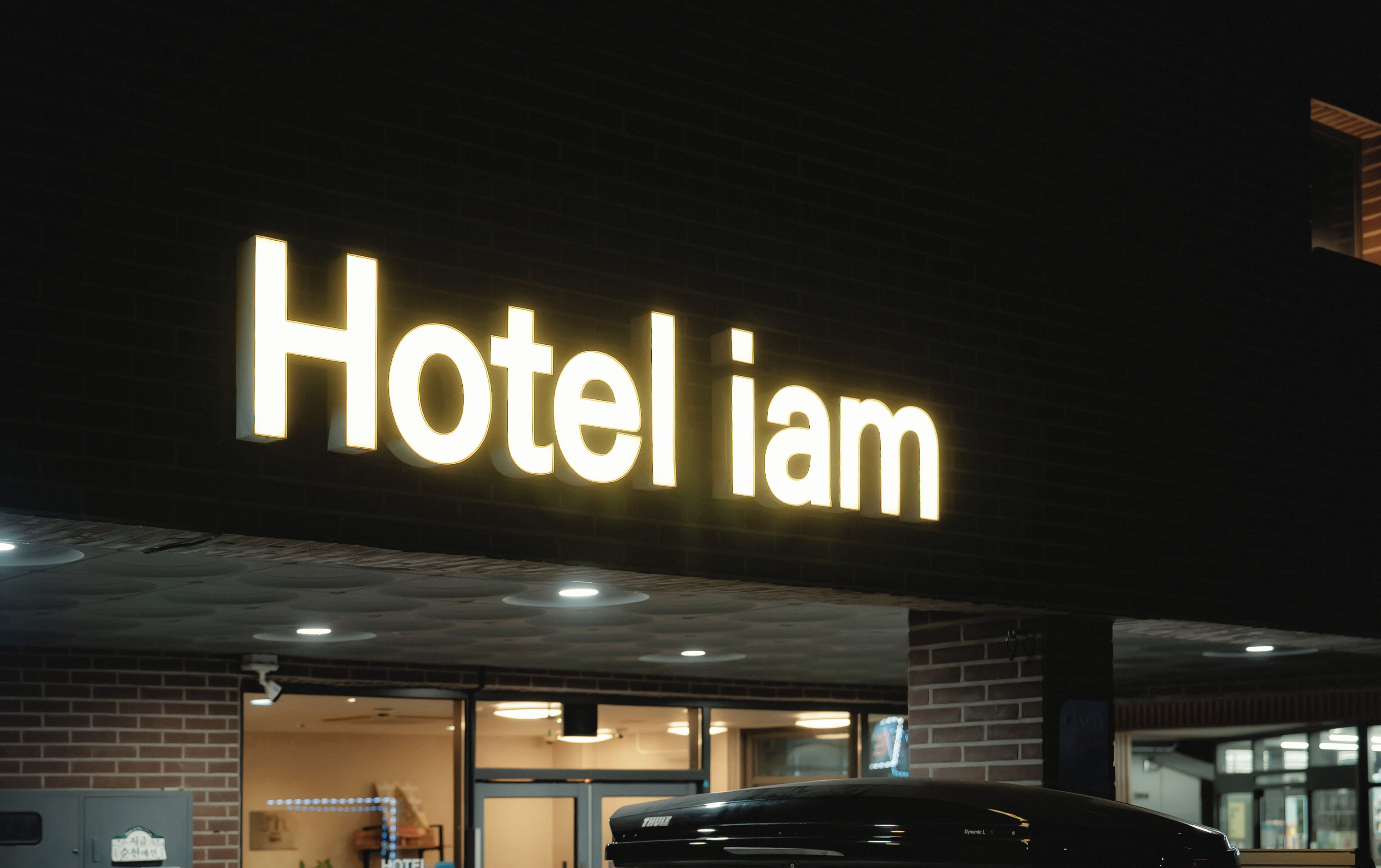 Señal de hotel con el nombre "Hotel iam" iluminado sobre un fondo oscuro.