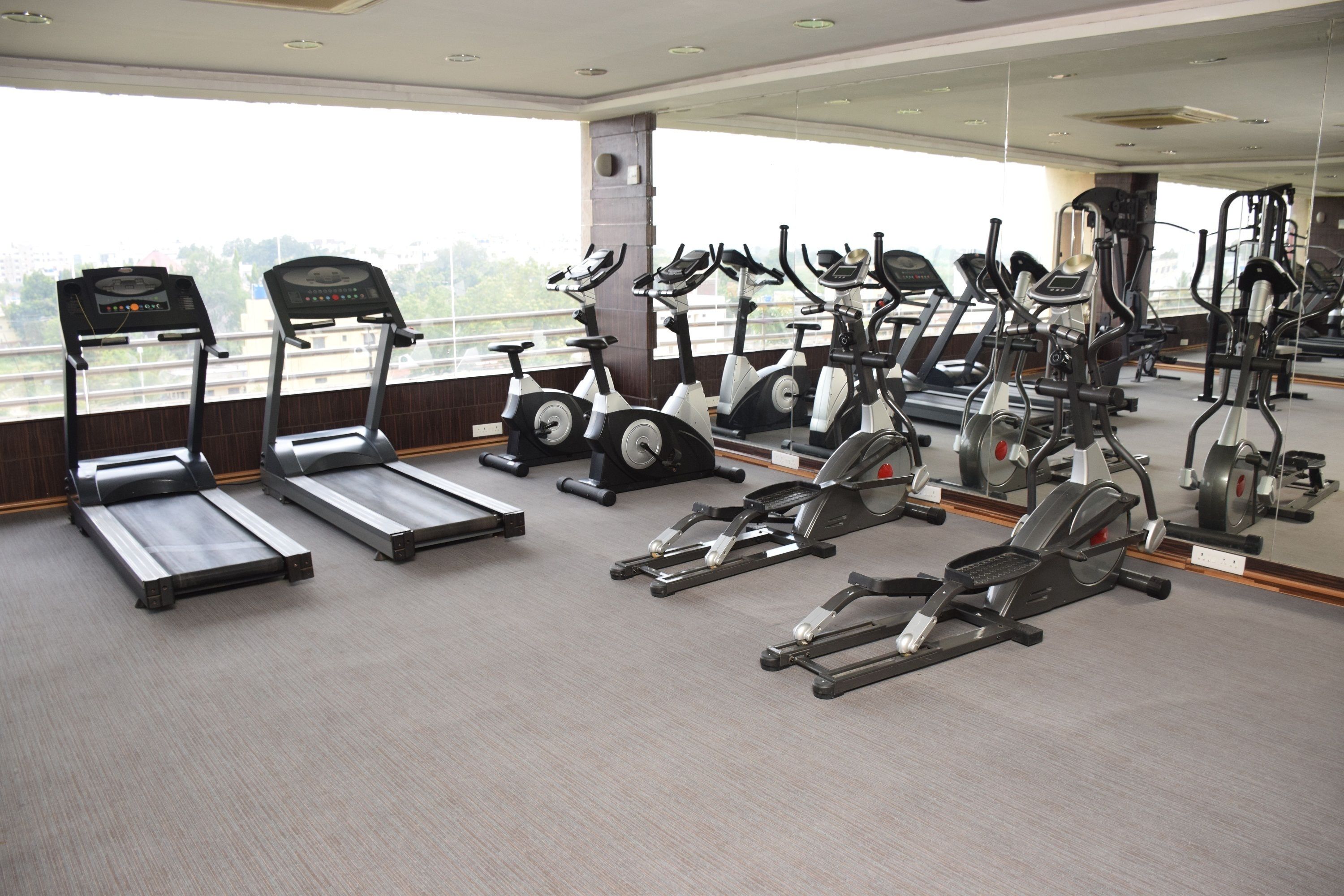 Un gimnasio con cintas de correr, bicicletas estáticas y elípticas.