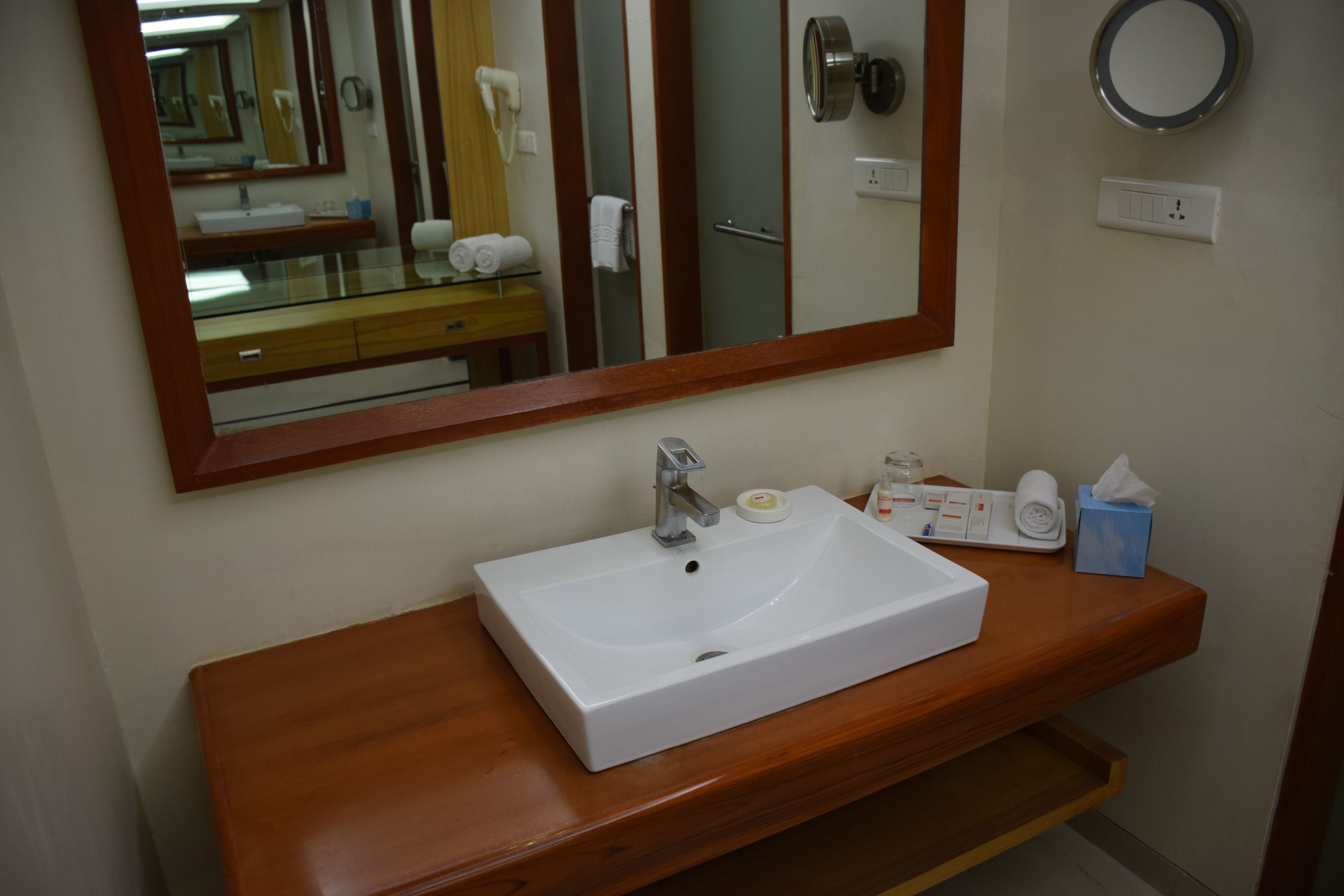 Une salle de bain avec un lavabo blanc, un meuble-lavabo en bois et un grand miroir.