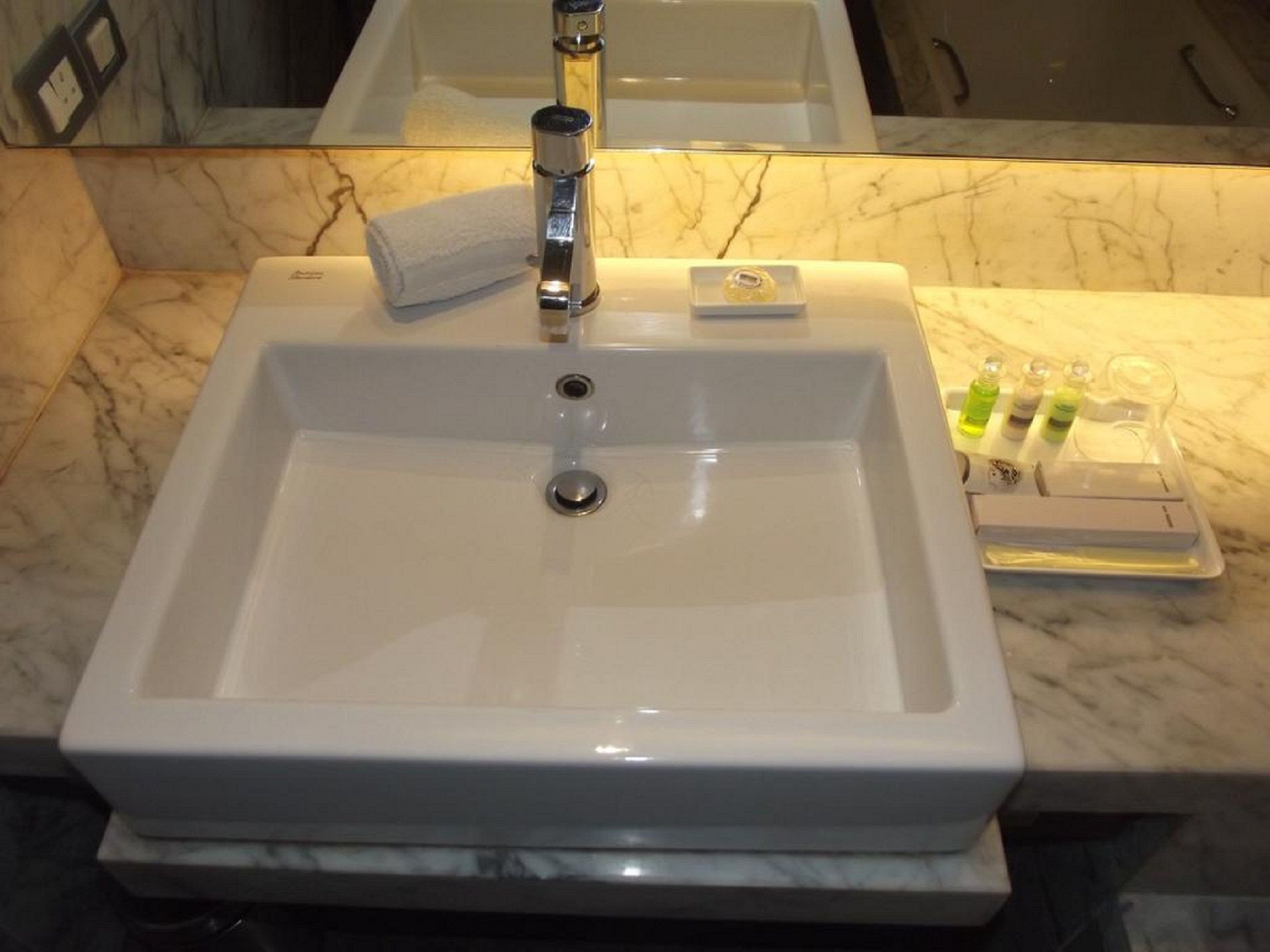 Une salle de bain avec un lavabo blanc, un miroir et des articles de toilette posés sur le comptoir.