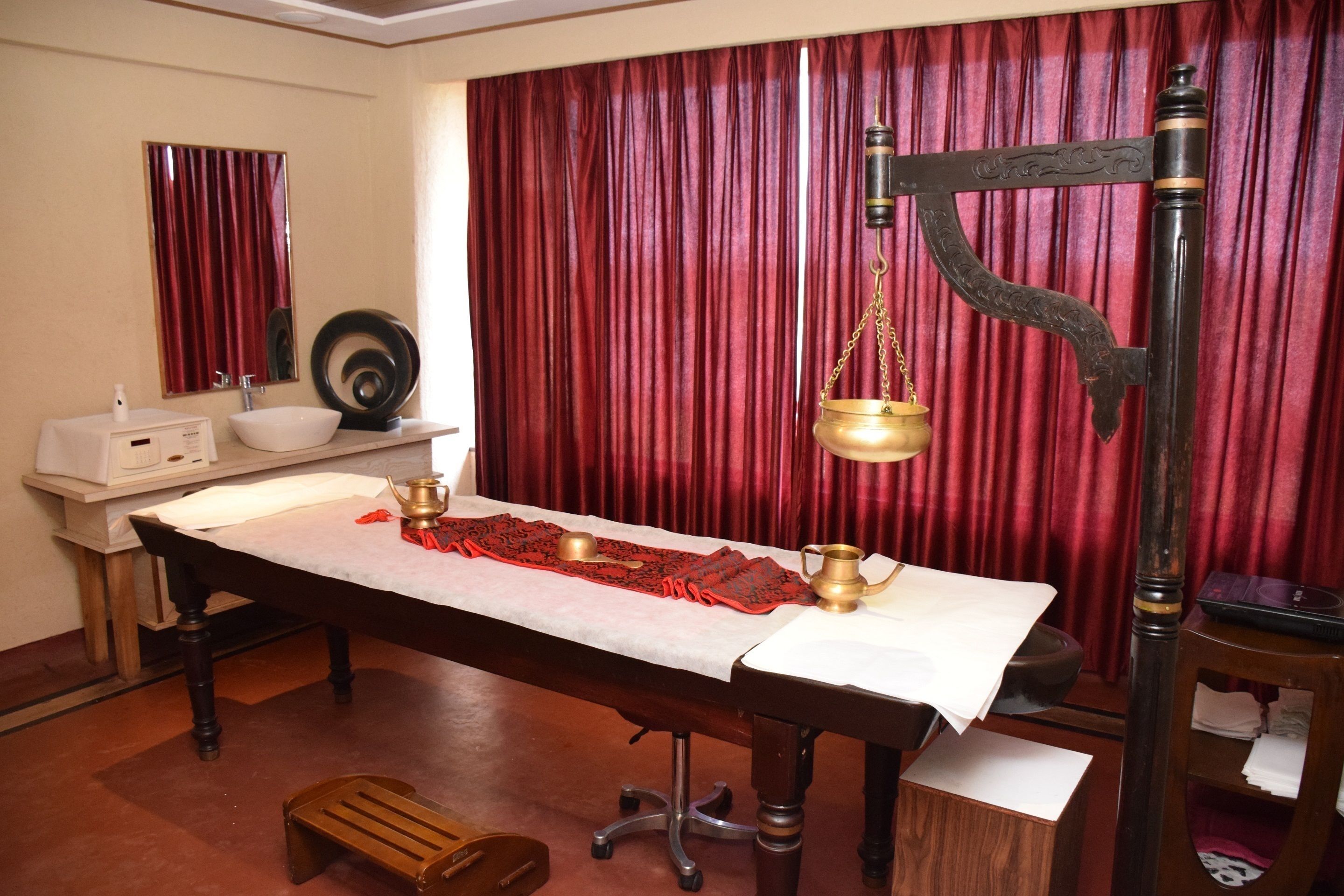 A traditional room with a long wooden table, a white basin, and a brass scale.