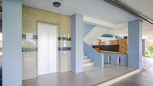 A spacious interior with a staircase, a door, and a wall with a textured pattern. - AJ Residence (Ratsada)