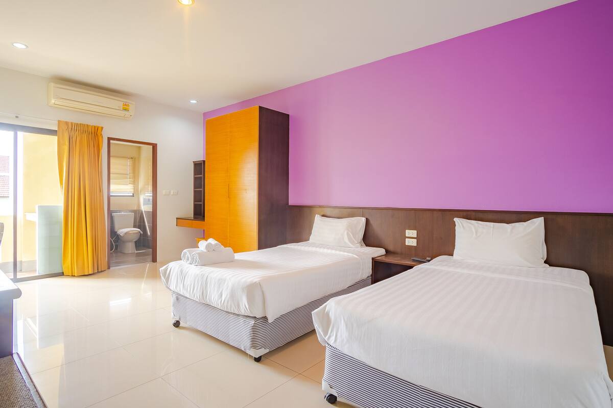 A hotel room with two beds, a bathroom, and a view of the outside.