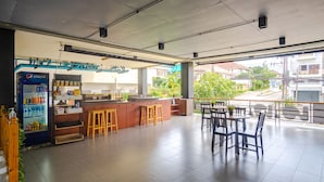 A spacious cafe with a counter, stools, and a seating area with tables and chairs. - AJ Residence (Ratsada)