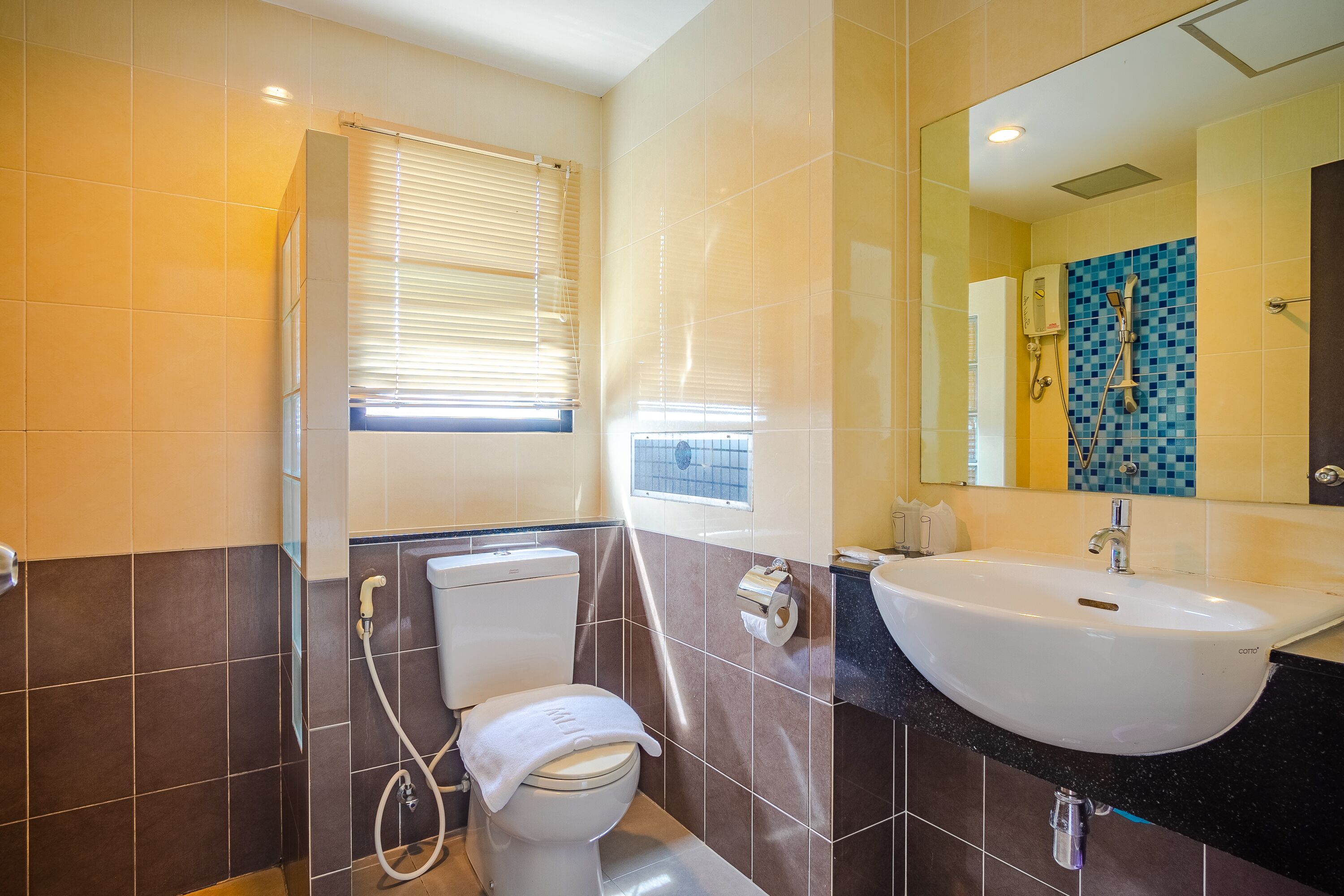A bathroom with a toilet, bidet, sink, and a mirror.