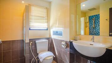 A bathroom with a toilet, bidet, sink, and a mirror.