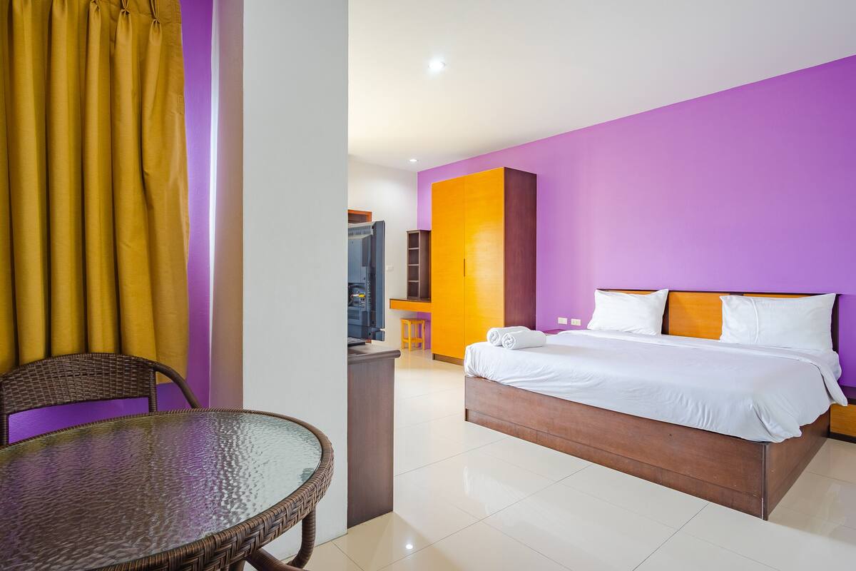 A hotel room with a bed, a dining table, and a small kitchen area.