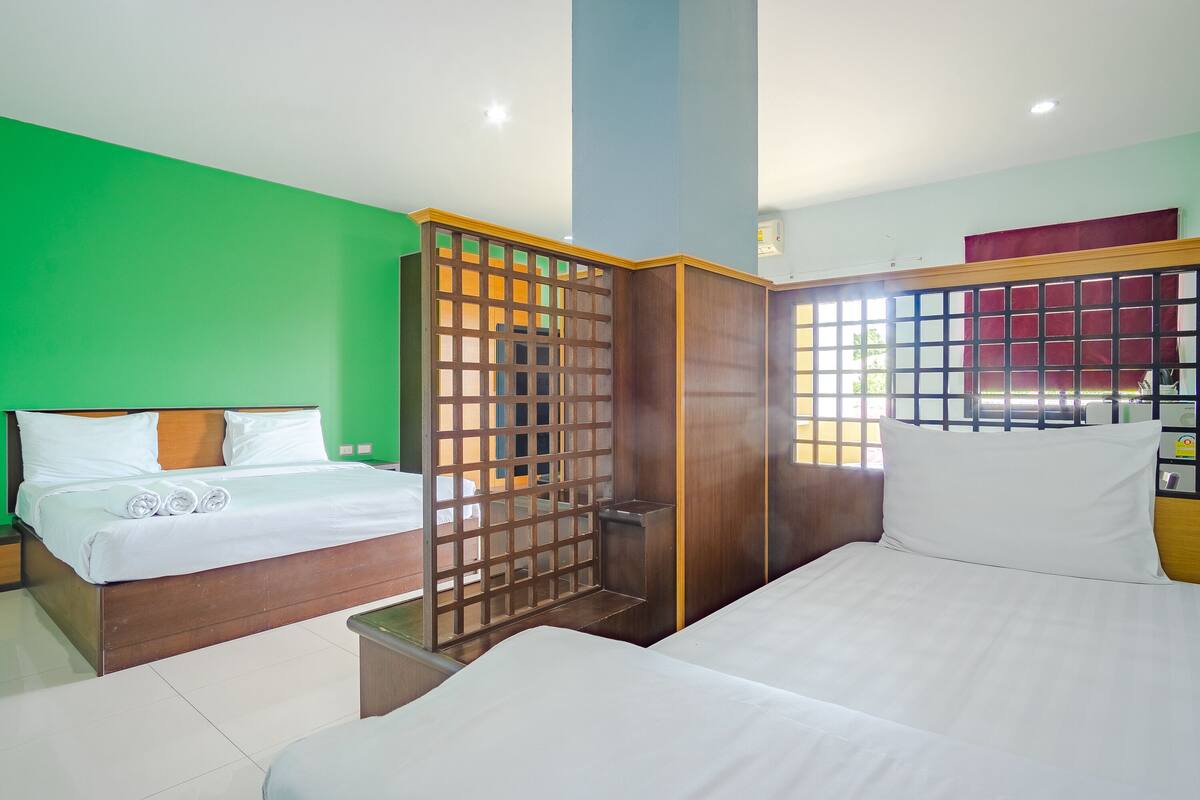 A hotel room with two beds, a wooden partition, and a view of the outside.