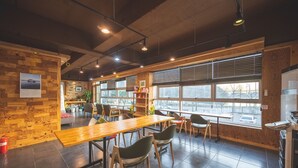 A spacious cafe with wooden walls, large windows, and a long wooden table with chairs. - B&F Hotel (Yeosu)