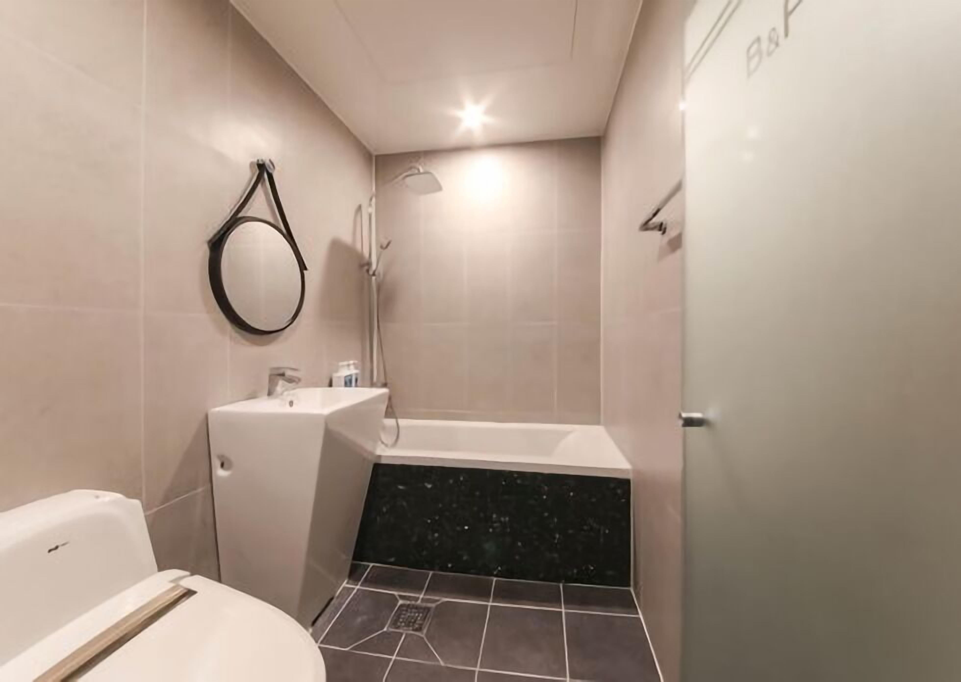 A modern bathroom with a toilet, sink, and bathtub.