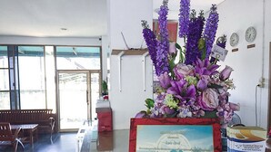 Ett välkomstområde med en marmorskiva, en stor blomsterarrangemang, ett inramat certifikat och en bänk.