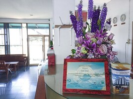A reception area with a marble counter, a large floral arrangement, a framed certificate, and a bench.