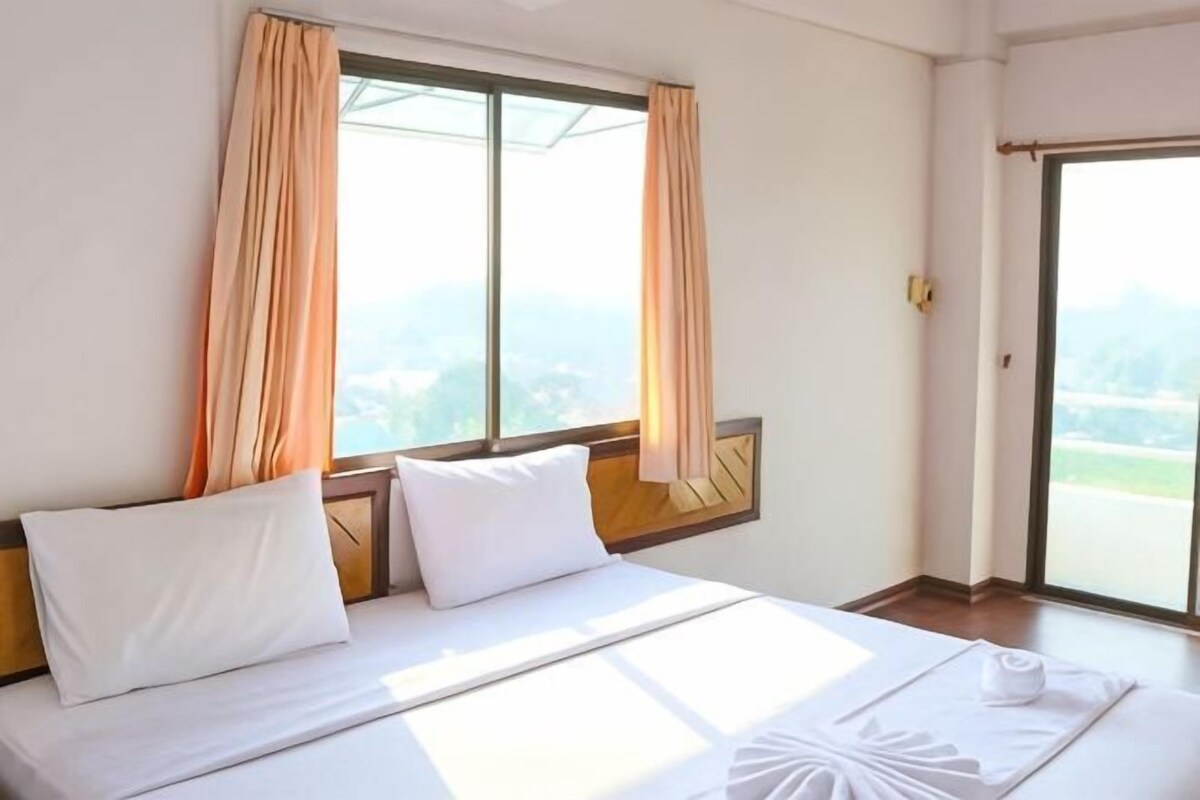 A hotel room with a bed, curtains, a window, and a view.