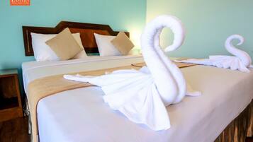 Una habitación de hotel con una cama bien hecha, un cabecero de madera y una mesita de noche fijada a la pared.
