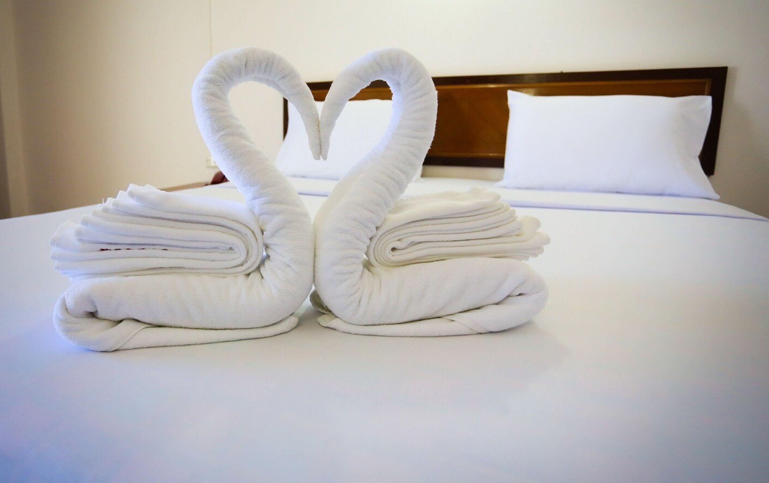 A neatly made bed with a heart-shaped towel arrangement in the center.