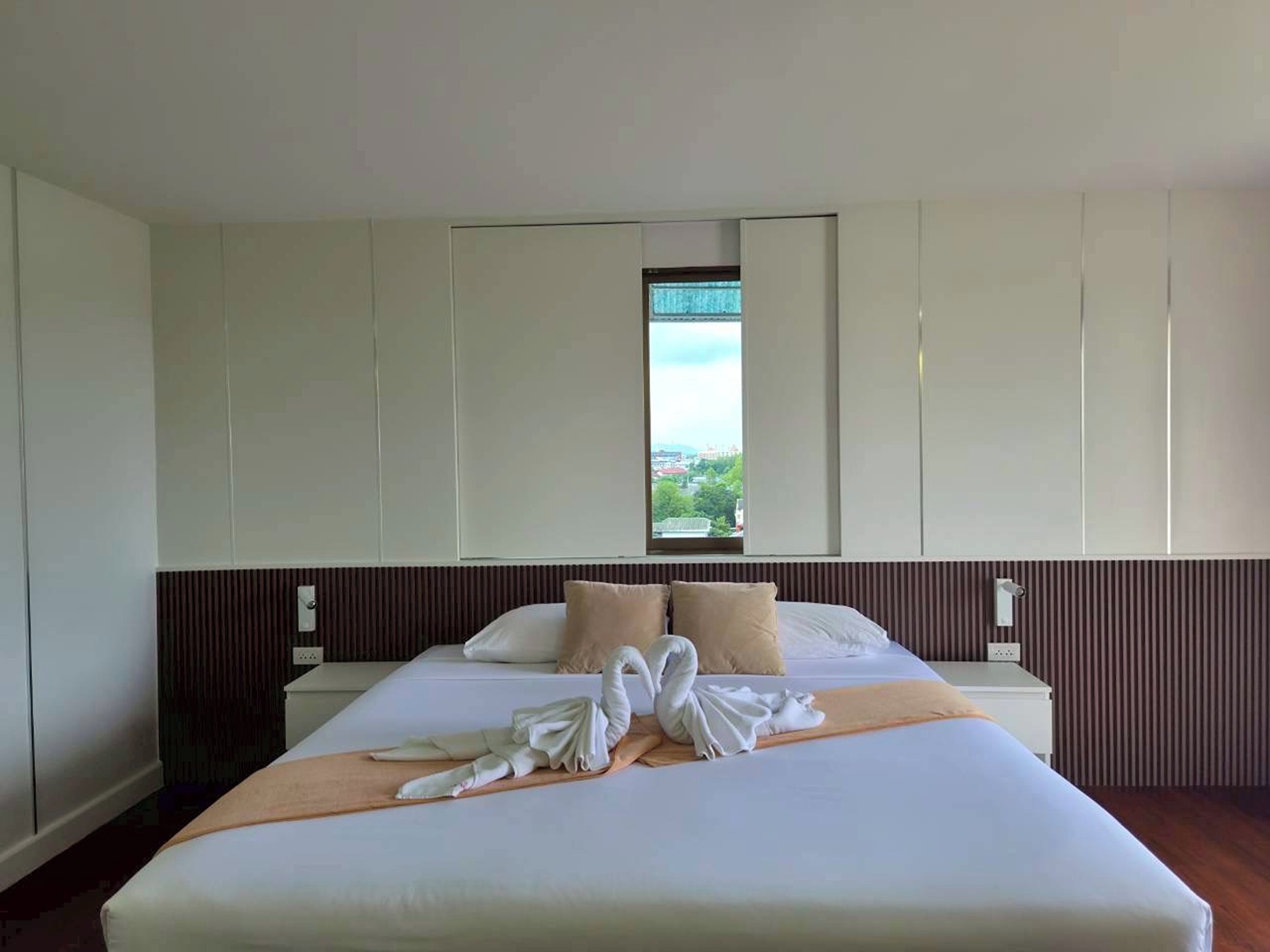 Habitación de hotel con una cama grande, ventana con vistas y pared de paneles de madera.