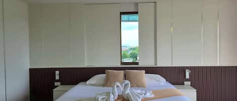 Habitación de hotel con una cama grande, ventana con vistas y pared de paneles de madera.