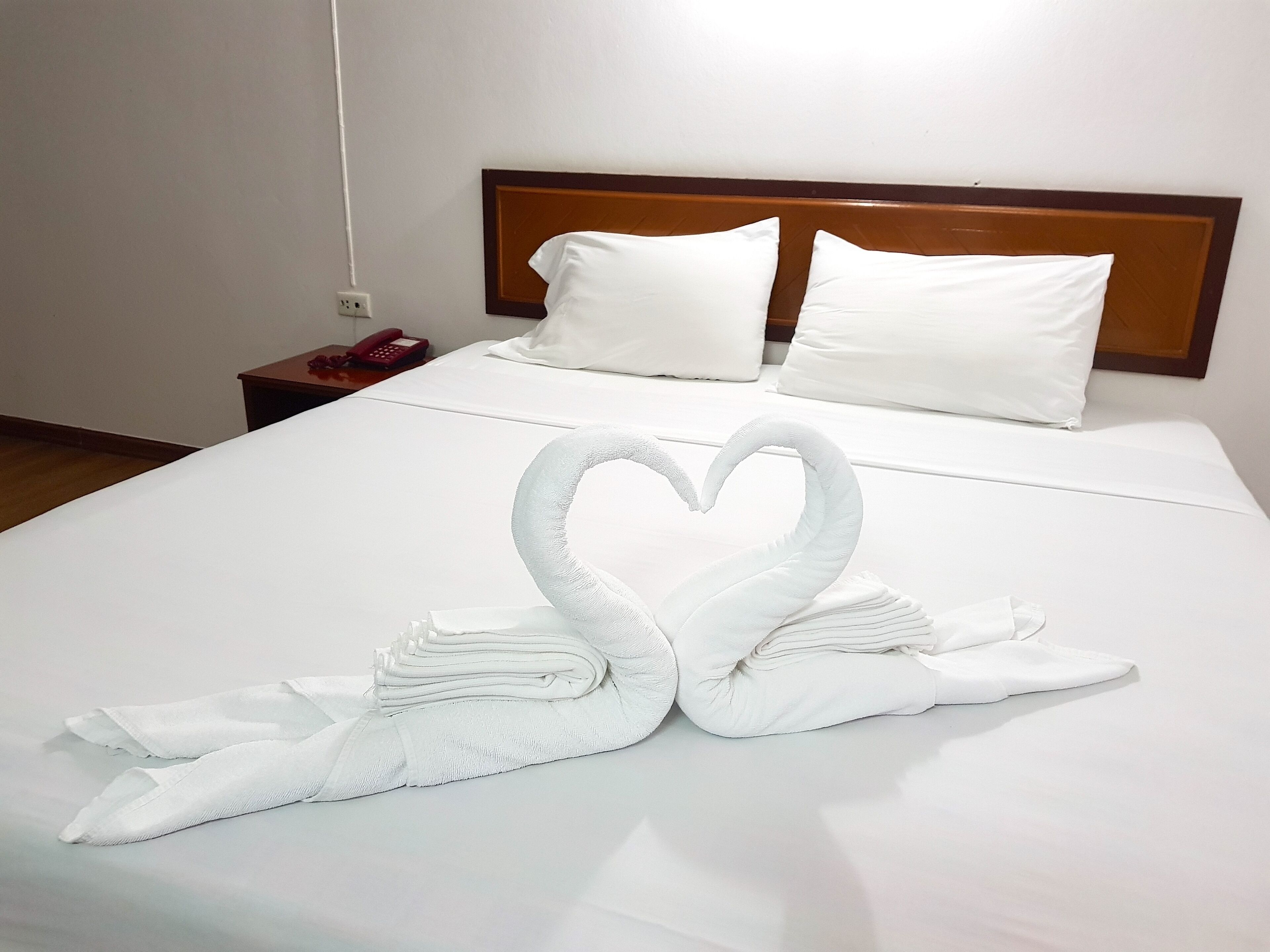 Habitación de hotel con una cama bien hecha, un cabecero de madera y un teléfono en la mesita de noche.