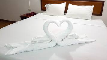 Habitación de hotel con una cama bien hecha, un cabecero de madera y un teléfono en la mesita de noche.