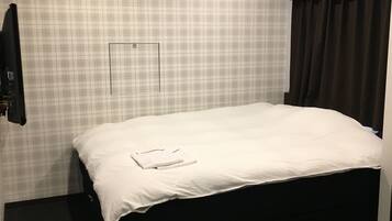 Quarto de hotel com cama grande, ar condicionado, cabeceira escura e padrão de parede xadrez.