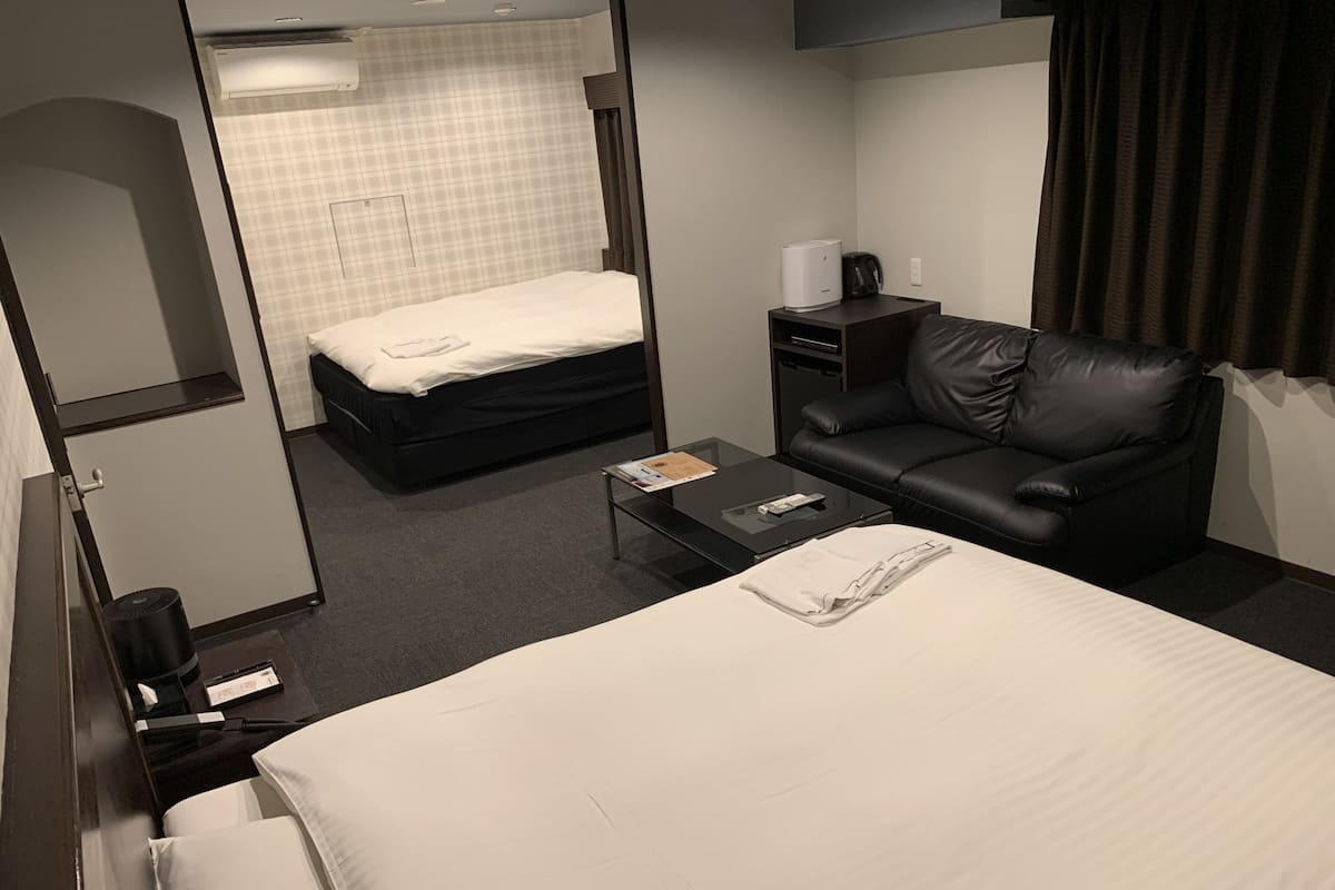 A hotel room with a bed, a sofa, a coffee table, a desk, and a wardrobe.